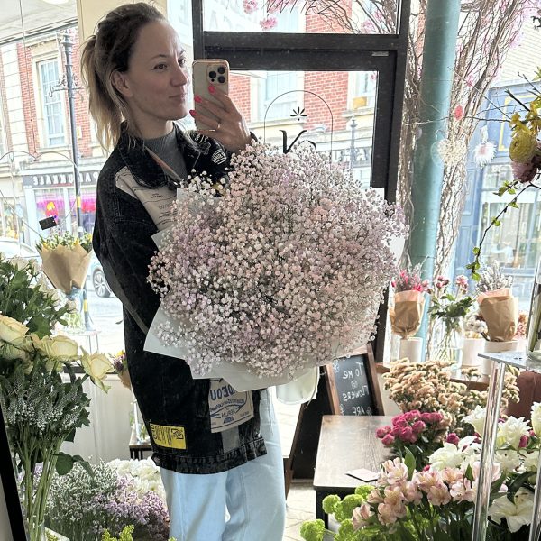Woman holding a large blush pink gypsophila bouquet inside KS Bloomery flower shop in Northampton.