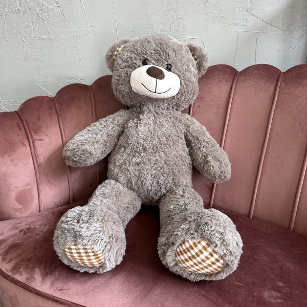 Grey plush teddy bear sitting on a pink velvet scallop-back sofa at KS Bloomery, Northampton.