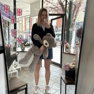 Woman holding a grey teddy bear inside KS Bloomery shop in Northampton.