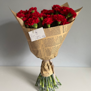 Rustic bouquet of red carnations wrapped in vintage-style newspaper with KS Bloomery tag.