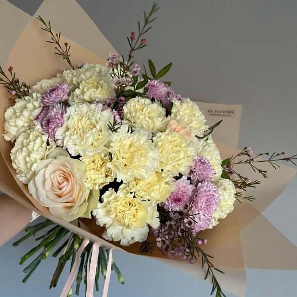 Delicate bouquet of cream carnations, soft pink roses, and lavender chrysanthemums with wild greenery.