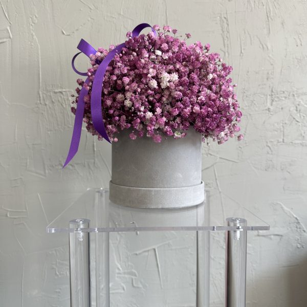 Purple and pink gypsophila bouquet in a round grey velvet hat box with a purple ribbon.