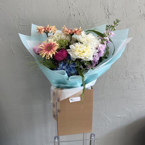 Bright summer bouquet with peonies, chrysanthemums, and blue hydrangeas in aqua wrapping.