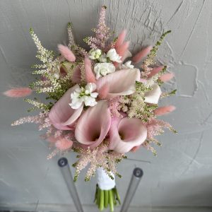 Elegant pink bridal bouquet with calla lilies, astilbe, and white flowers, wrapped with white ribbon.