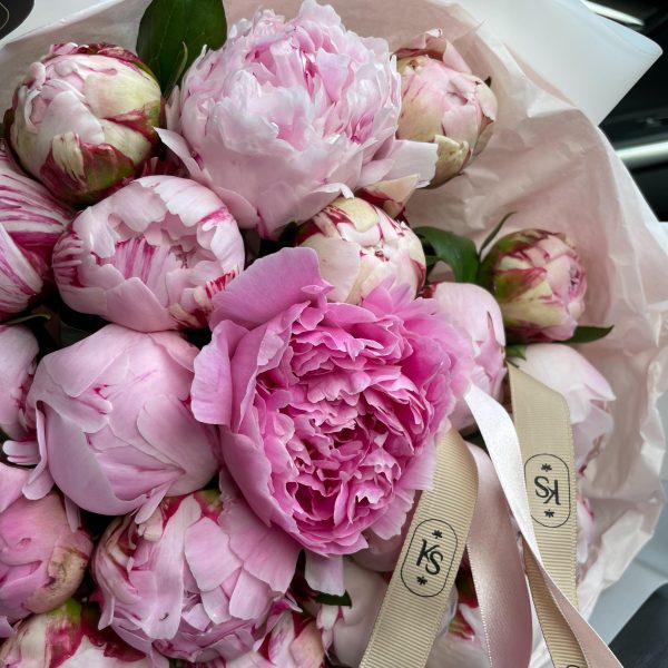 Close-up of a bouquet of pink peonies with KS Bloomery branded ribbon