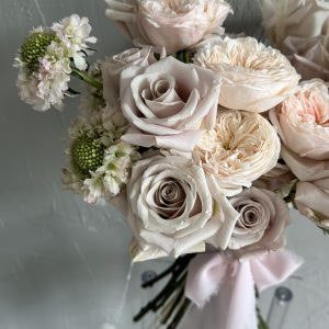 Elegant bouquet of blush and champagne roses with white scabiosa, finished with a pale pink ribbon.