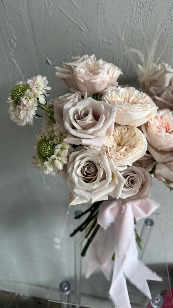 Elegant bouquet of blush and champagne roses with white scabiosa, finished with a pale pink ribbon.