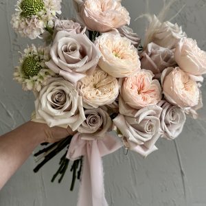 Hand-tied bouquet of blush garden roses, pale taupe roses, and soft green scabiosa, finished with a pink ribbon.