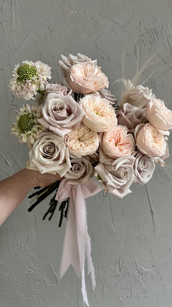 Hand-tied bouquet of blush garden roses, pale taupe roses, and soft green scabiosa, finished with a pink ribbon.