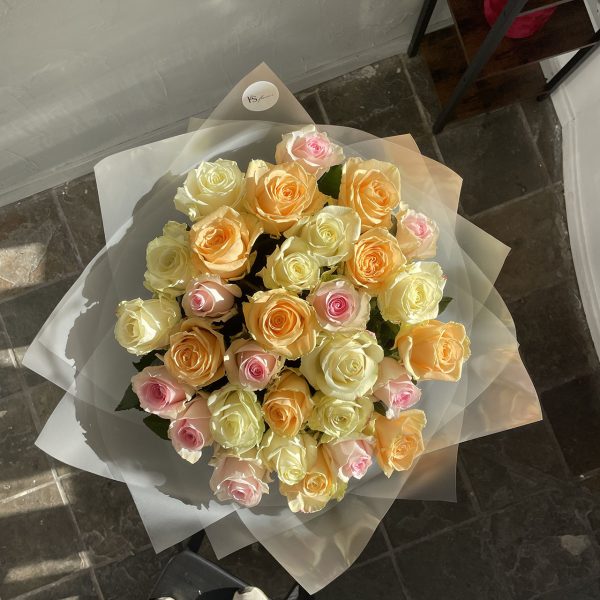 Stunning bouquet of mixed pastel roses in yellow, peach, ivory, and soft pink, arranged in frosted wrapping with KS Bloomery branding.