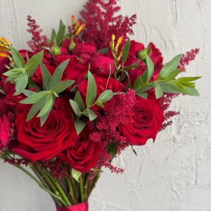 Red bridal bouquet featuring roses, astilbe, and lush green foliage.