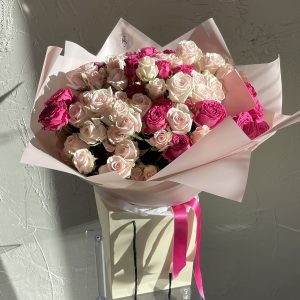 Bouquet of soft pink and fuchsia spray roses in pastel pink wrapping with satin ribbons.
