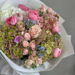 Luxurious bouquet with pastel pink roses, ranunculus, hydrangeas and delicate seasonal blooms.