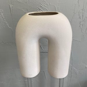 Modern beige ceramic vase with curved arch design.