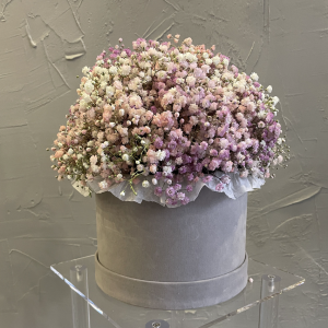 Muted lilac and pastel pink gypsophila bouquet arranged in a soft grey velvet hat box.